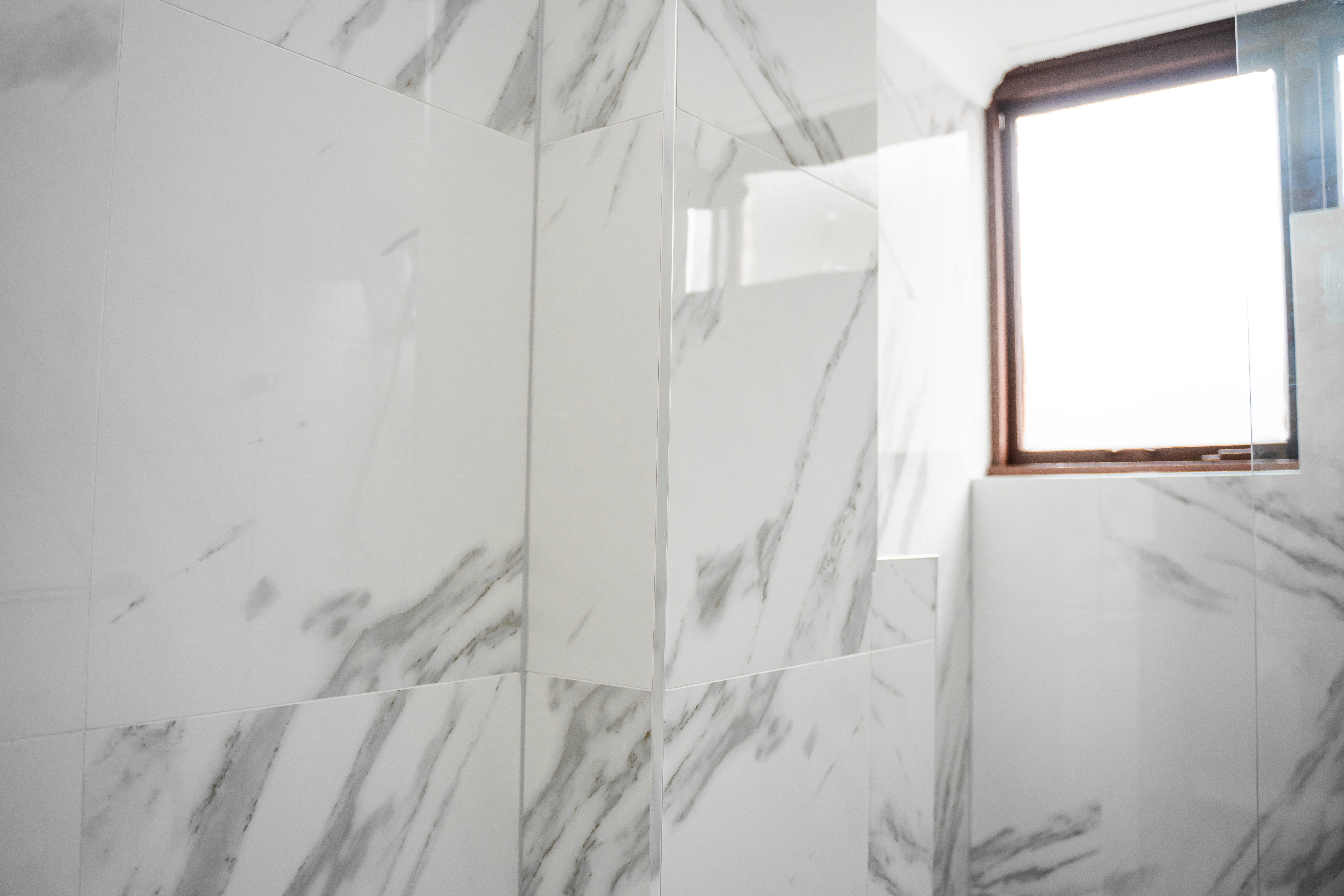 Tiled corner detail — marble walls meeting at window with clean tile joins