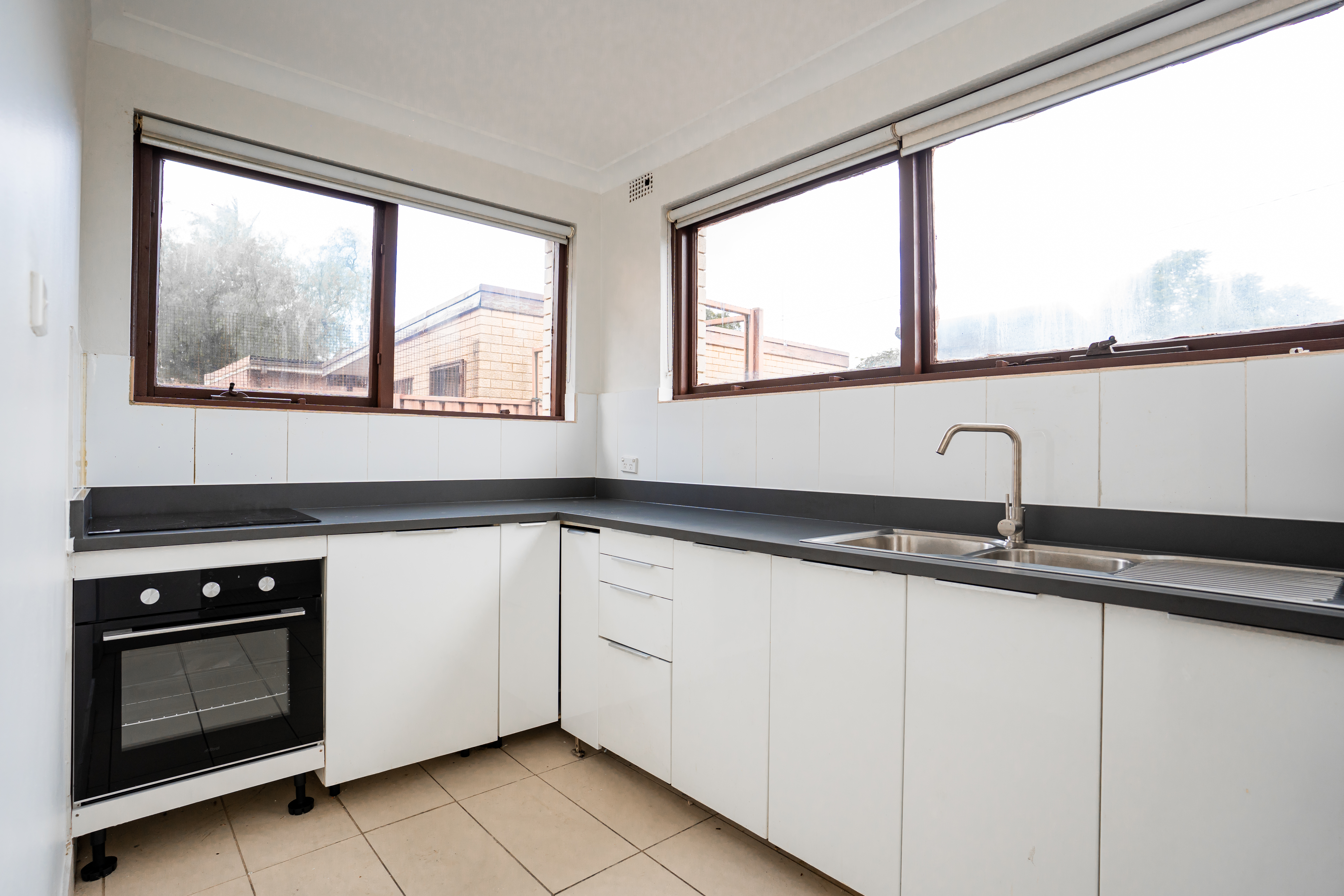 Full kitchen — L-shaped layout with white tile splashback and floor tiling