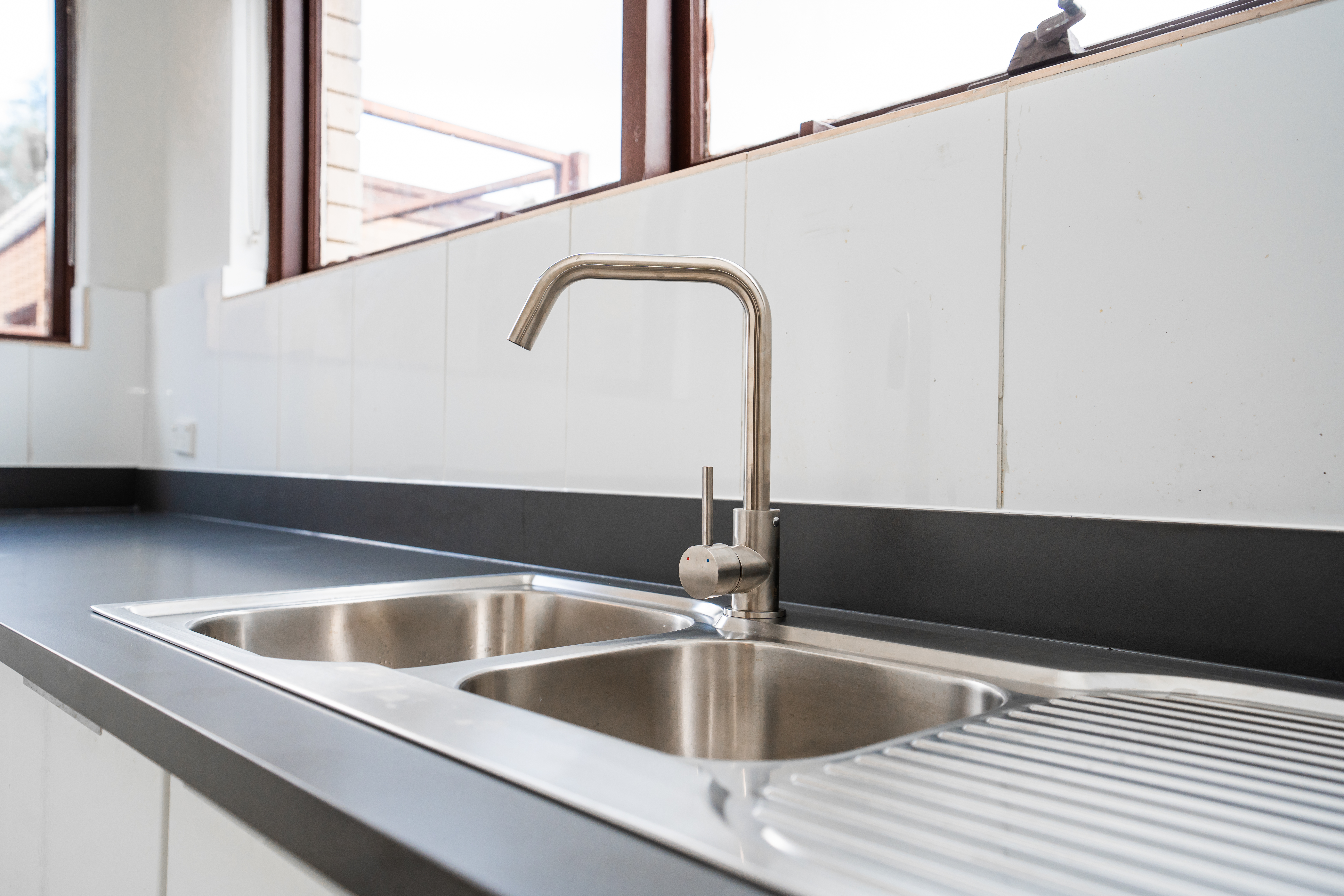Kitchen sink detail — stainless steel on tiled splashback