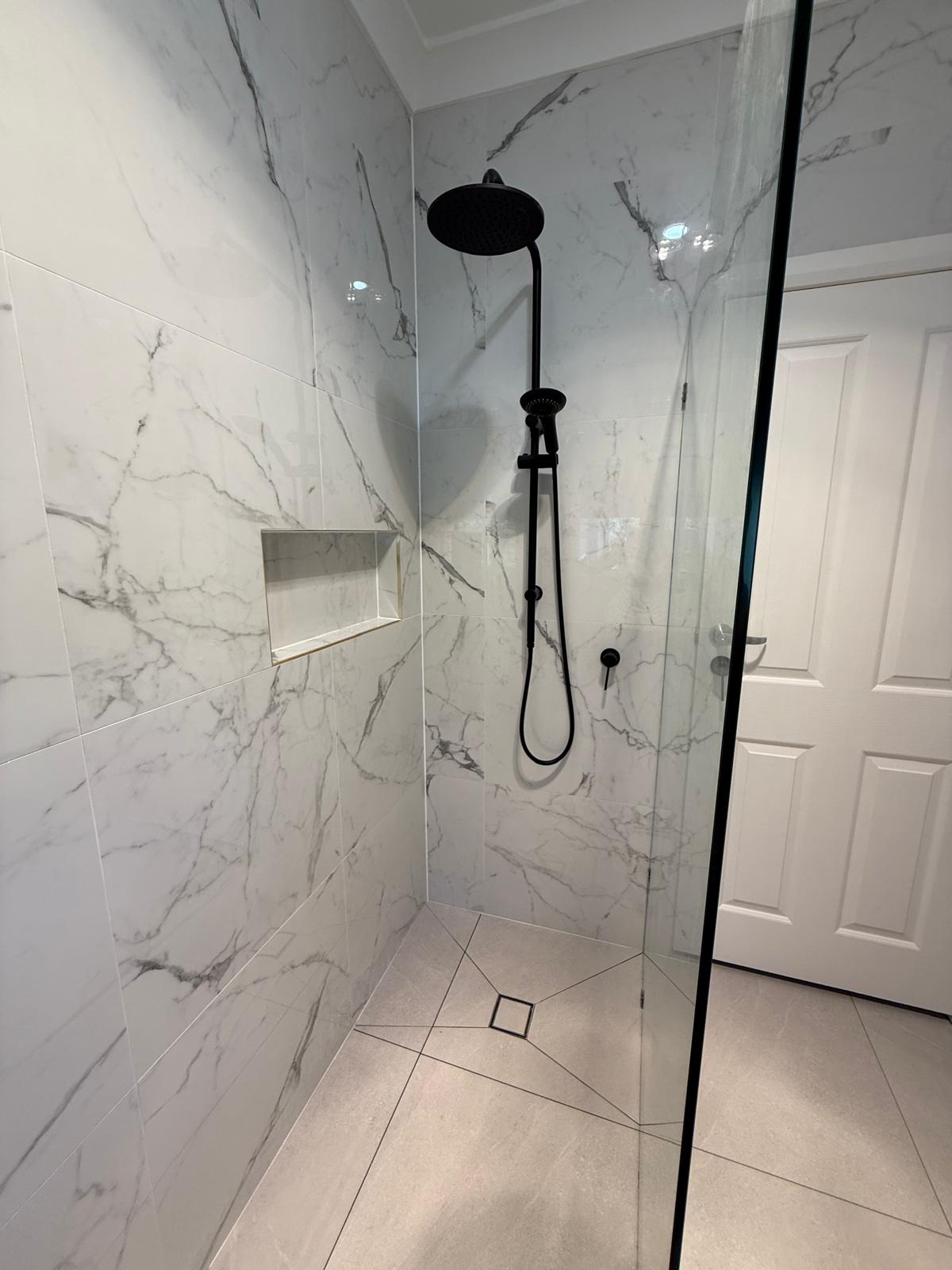 Marble bathroom renovation — shower with black fixtures