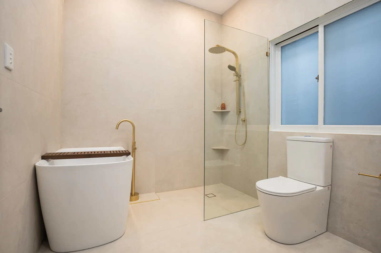 Full bathroom renovation — large-format porcelain tiles, freestanding bath, walk-in shower with brushed gold tapware