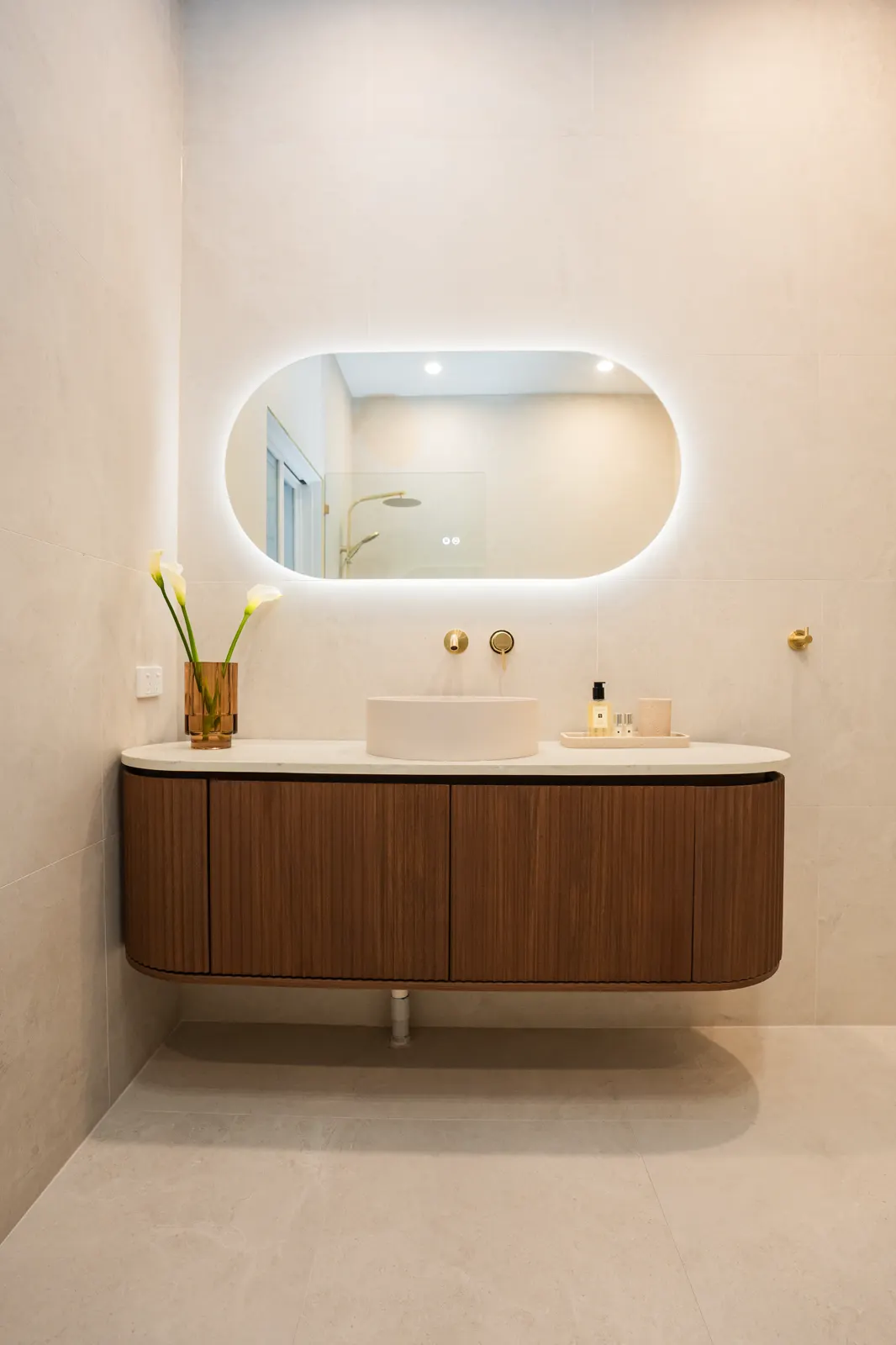 Freestanding bath with brushed gold floor-mounted filler on large-format limestone-look floor tiles