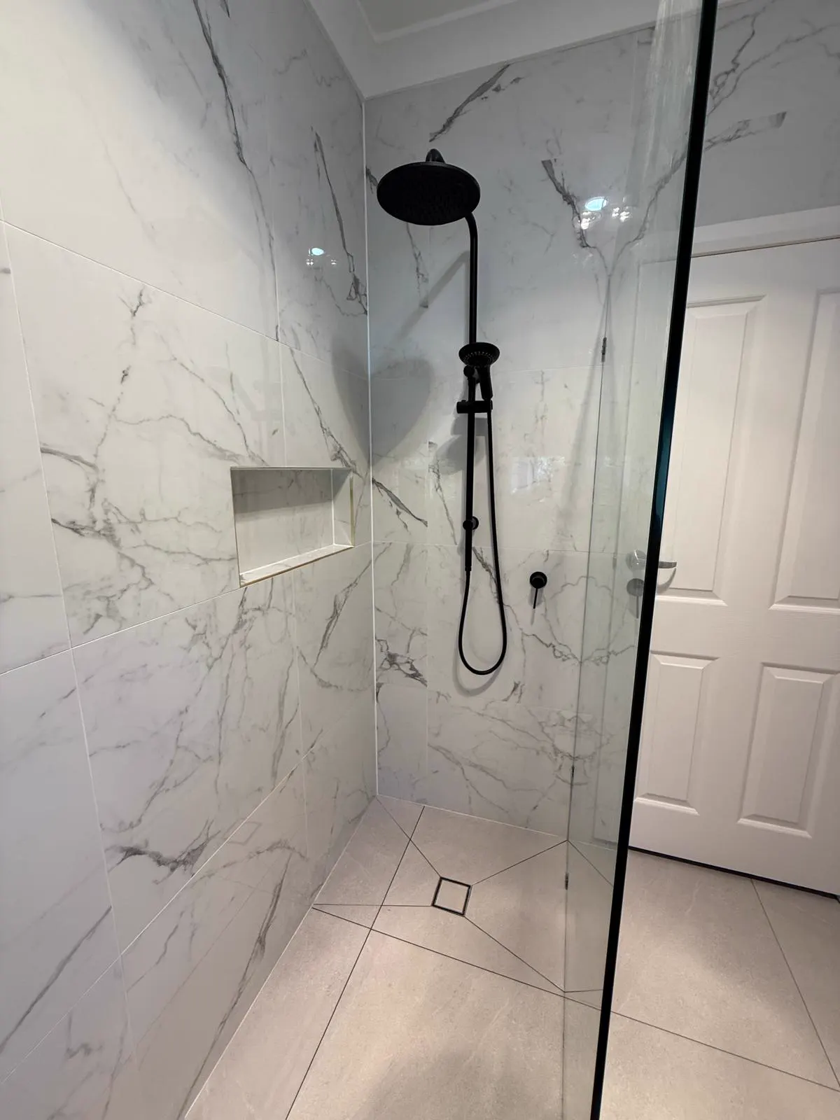 Marble bathroom renovation — shower with black fixtures
